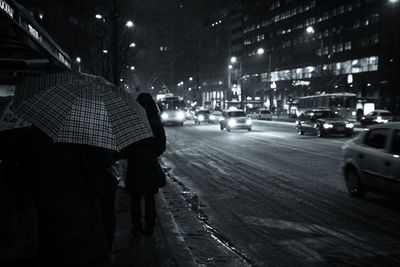 Rear view of people walking on road at night