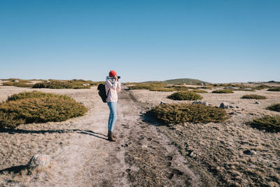 Rear view of a man walking on landscape against clear sky