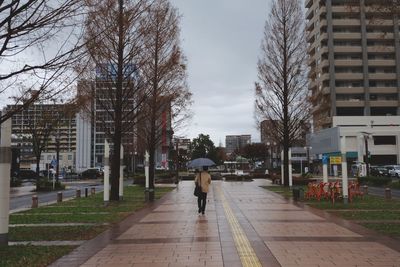 Rear view of man walking on street amidst buildings