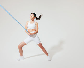 Full length of woman exercising against white background