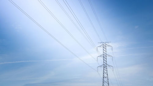 Low angle view of electricity pylon against blue sky