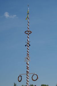 Low angle view of decorated pole against blue sky