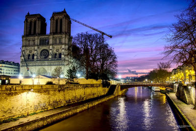 Arch bridge over river amidst buildings in city