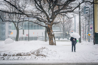 Rear view of man walking on snow covered city