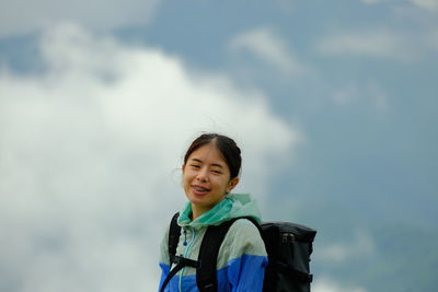 Low angle view of young woman standing against sky