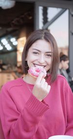 Portrait of smiling woman eating donut
