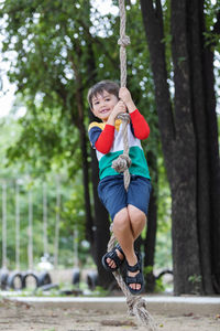 Boy with umbrella against trees