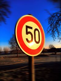 Close-up of road sign against blue sky