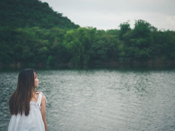 Rear view of woman looking at lake against trees