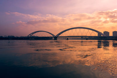 Bridge over river against sky during sunset