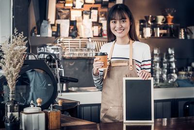 Portrait of a smiling young woman standing in cafe