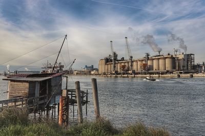 View of factory by sea against sky