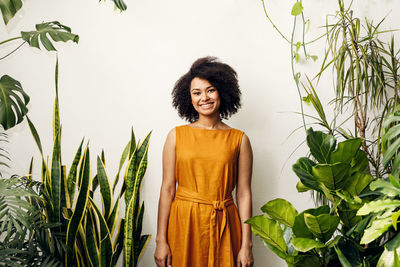 Portrait of smiling young woman standing against plants