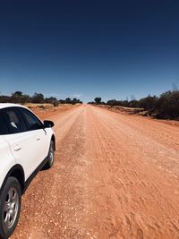 Car on dirt road against clear sky