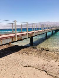 Bridge over sea against clear blue sky