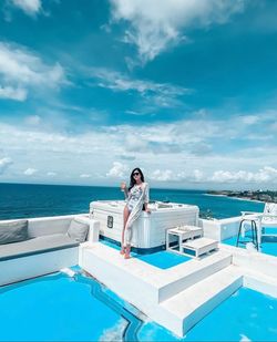 Woman standing by swimming pool against sea