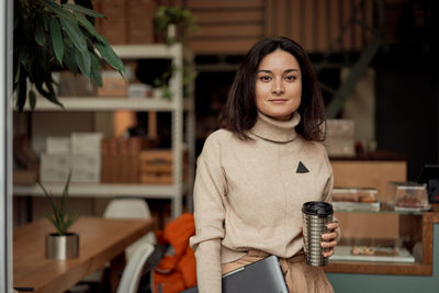 Portrait of smiling woman holding coffee cup at cafe