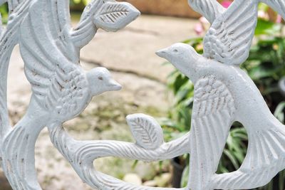 Close-up of bird perching on statue