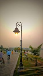 Illuminated street light against sky at sunset