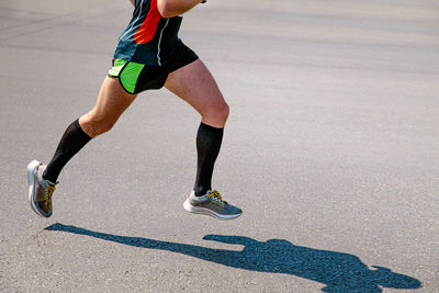 Low section of man skateboarding on road