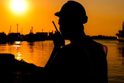 Silhouette man standing by sea against sky during sunset