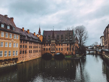 Bridge over canal amidst buildings in city against sky