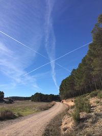 Landscape against vapor trail in sky