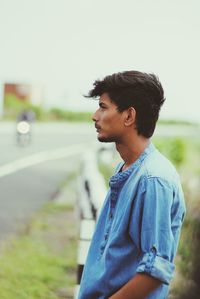 Side view of young man looking away on roadside