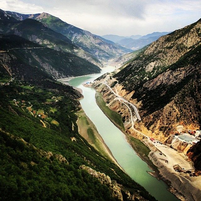 mountain, water, mountain range, high angle view, built structure, sky, river, scenics, architecture, building exterior, nature, beauty in nature, sea, tranquil scene, tranquility, landscape, day, cloud - sky, tree, outdoors