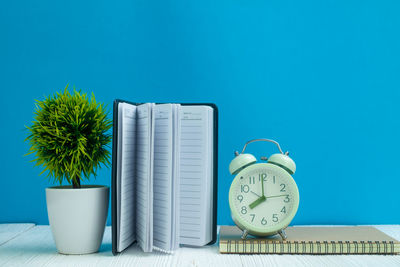 Close-up of clock on table against blue background