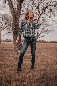 Portrait of smiling young woman standing on bare tree