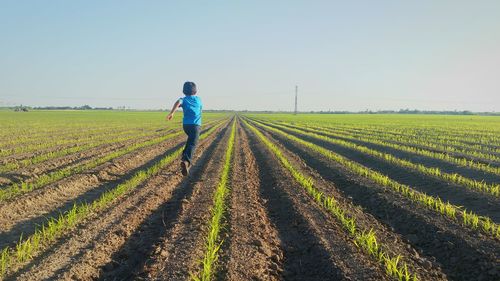 Side view of kid running in agricultural field