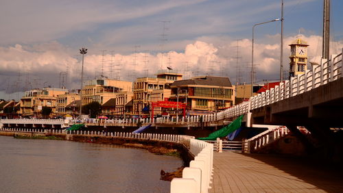 Bridge over river amidst buildings in city against sky