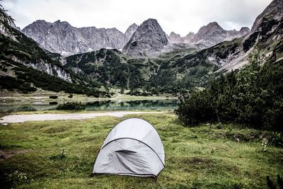 Tent by lake against mountain range