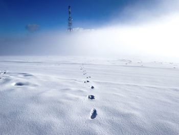 Footprints in the snow leading to a tower in the distance