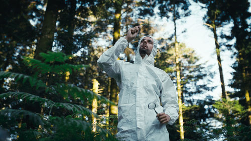 Plant biologist inspecting the leaf of a tree in the mountains