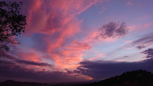 Low angle view of silhouette trees against dramatic sky