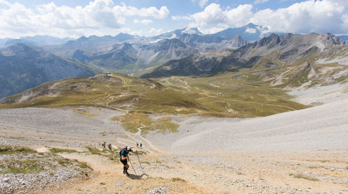 Rear view of man walking on mountain against sky