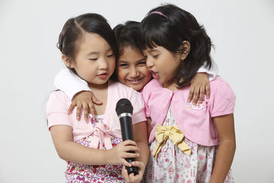 Girls singing on microphone against white background