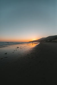 Scenic view of beach against clear sky during sunset