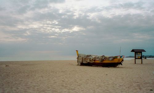 Abandoned boat on beach against sky