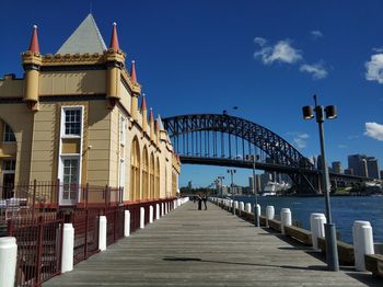 Bridge over river amidst buildings against blue sky