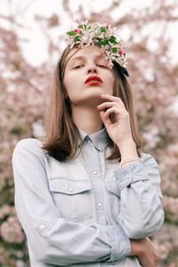 Portrait of beautiful young woman standing against white wall