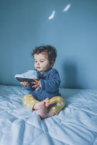 Cute girl playing with shoe on bed at home