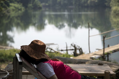 Side view of woman napping by lake