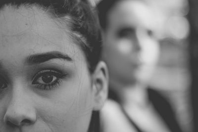 Close-up portrait of young woman with friend in background