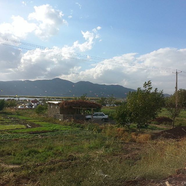 mountain, sky, mountain range, landscape, tranquil scene, built structure, house, tranquility, cloud - sky, nature, building exterior, scenics, architecture, grass, cloud, beauty in nature, village, day, field, non-urban scene