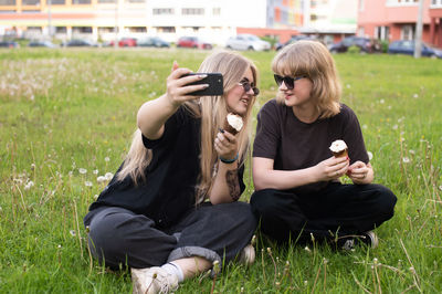 Side view of young woman sitting on grassy field