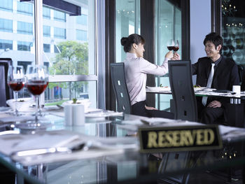 Close-up of reserved sign on table against businessman and businesswoman at restaurant