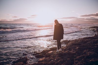 Silhouette woman standing at beach during sunset